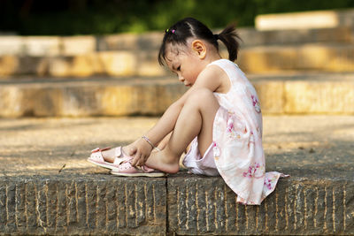 Girl looking away while sitting outdoors