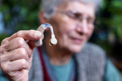 Upset senior woman showing a hearing aid