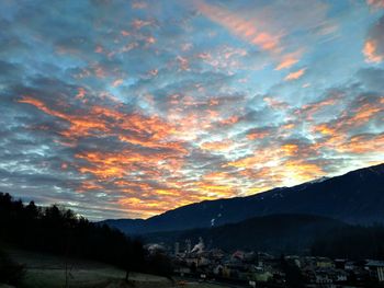 Scenic view of dramatic sky over silhouette mountains during sunset