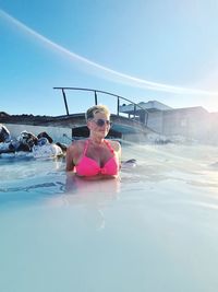 Woman in pink swimming pool against sky