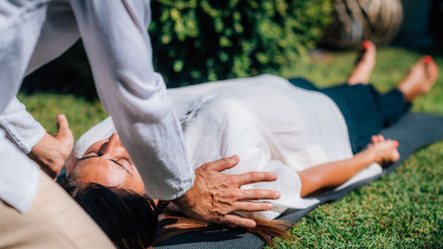 Reiki therapist holding hands over the shoulders of a peaceful woman