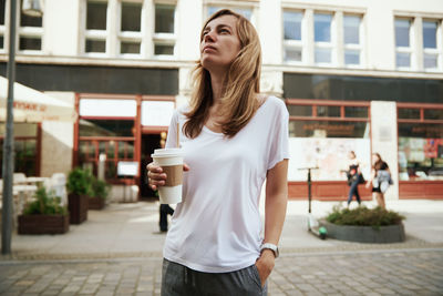 Coffee paper cup in woman hands. woman drinks coffee to go at city street.