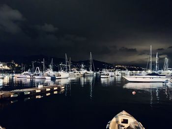 Sailboats moored in harbor at night