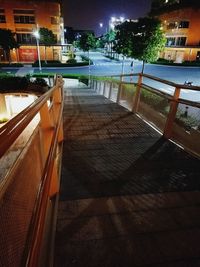 Empty footpath by swimming pool in city at night