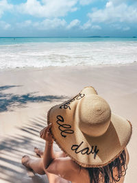 Man wearing hat on sand at beach against sky