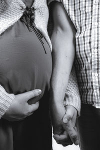 Midsection of pregnant woman holding hands with boyfriend