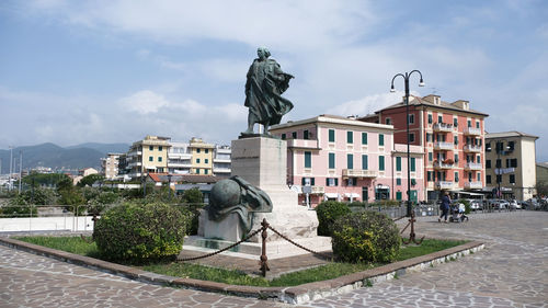 Statue by street against buildings in city against sky