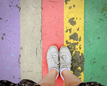 Low section of man standing on multi colored umbrella