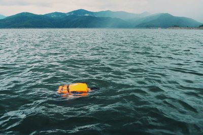 High angle view of man swimming in sea against mountains