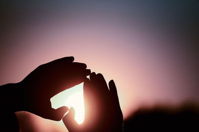 Silhouette hand holding sun during sunset