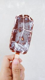 Close-up of person holding ice cream over white background