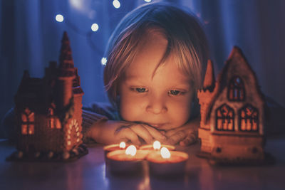 Portrait of boy with illuminated candles on table