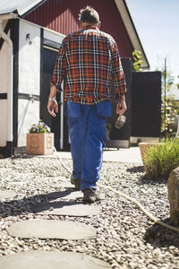 Full length of senior man holding hammer while walking at yard