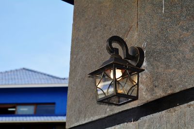 Low angle view of electric lamp on building against sky