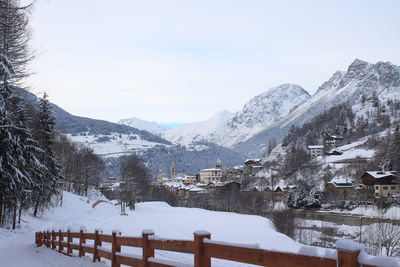 Snow covered houses and mountains against sky