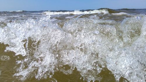 Close-up of waves splashing in sea against sky