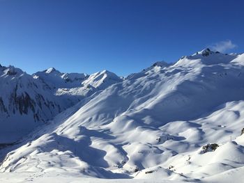 Scenic view of snowcapped mountains against clear blue sky