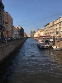 Canal amidst buildings in city against sky