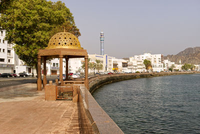 Buildings by river against clear sky