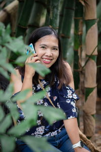 Portrait of smiling woman sitting by plants