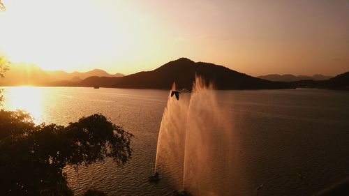 Silhouette man by sea against sky during sunset