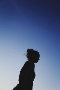 Low angle view of silhouette girl standing against clear blue sky