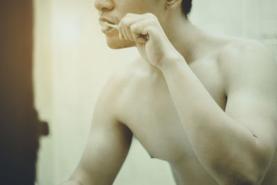 Midsection of shirtless man brushing teeth