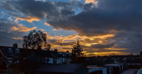 Silhouette trees and buildings against sky during sunset