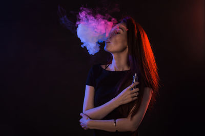 Young woman looking away against black background