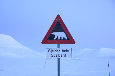 Close-up of road sign against clear blue sky