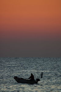 Silhouette person in sea against sky during sunset