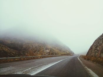 Road by mountains against clear sky