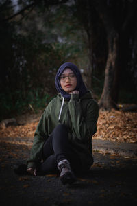 Portrait of young woman sitting in forest