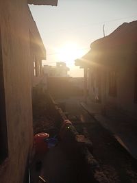 Street amidst buildings against sky during sunset