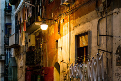 Laundry drying on clothesline next to illuminated lamp outside building