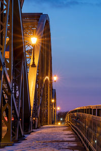 Bridge over illuminated street against sky at night