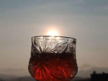 Close-up of wine glass against sky during sunset