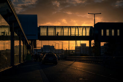 Cars on bridge in city against sky during sunset