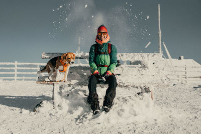 Full length of woman sitting on snow covered land