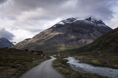 Road amidst snowcapped mountains against sky