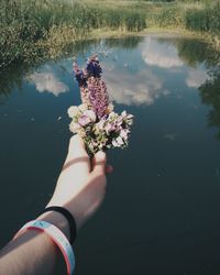 Close-up of hand with flowers in lake