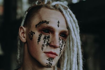 Close-up of man with spooky eyes and tattoo on face