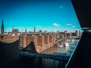 Bridge over river amidst buildings in city against blue sky