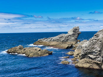 Scenic view of rocks in sea against blue sky