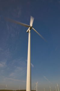 Low angle view of windmill against blue sky