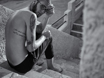 High angle portrait of tattooed young man sitting on steps