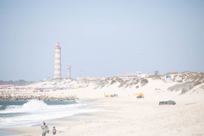 People at beach against clear sky