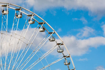 Low angle view of people on ferris wheel against cloudy sky
