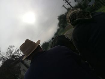 Rear view of man holding umbrella against sky