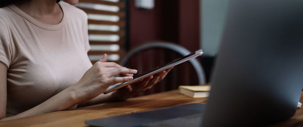 Midsection of woman using digital tablet